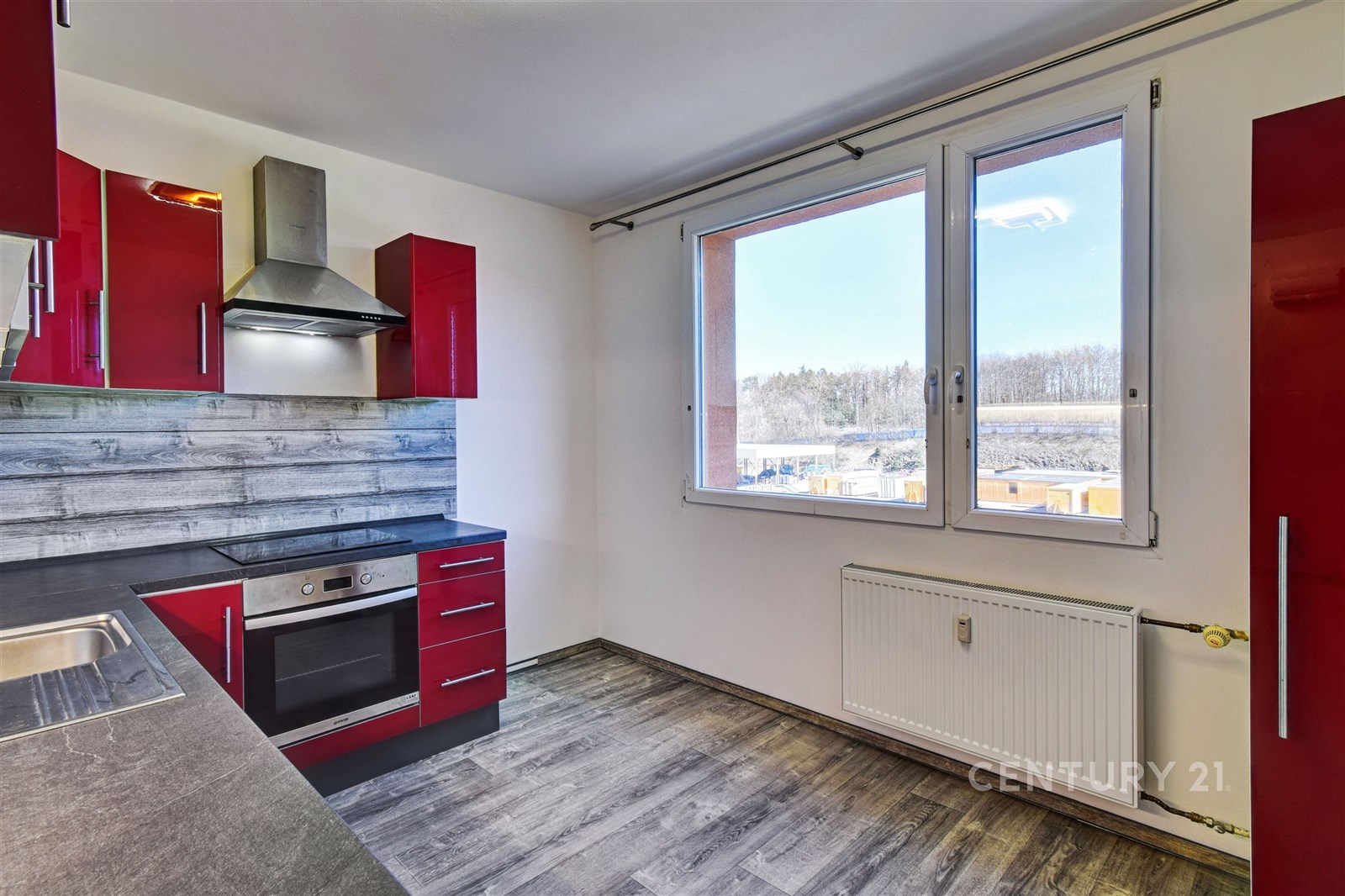 Moderní kuchyň s červenými skříňkami, dřevěným obk