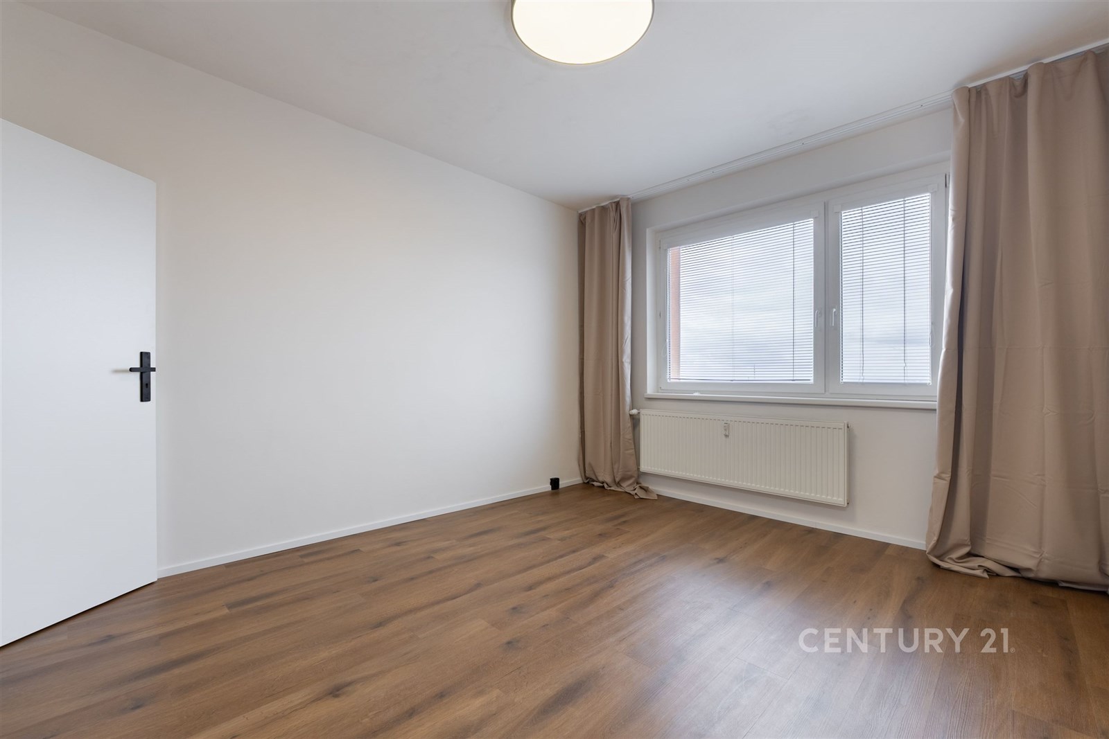 Prázdný pokoj s parketovou podlahou, velkým oknem 