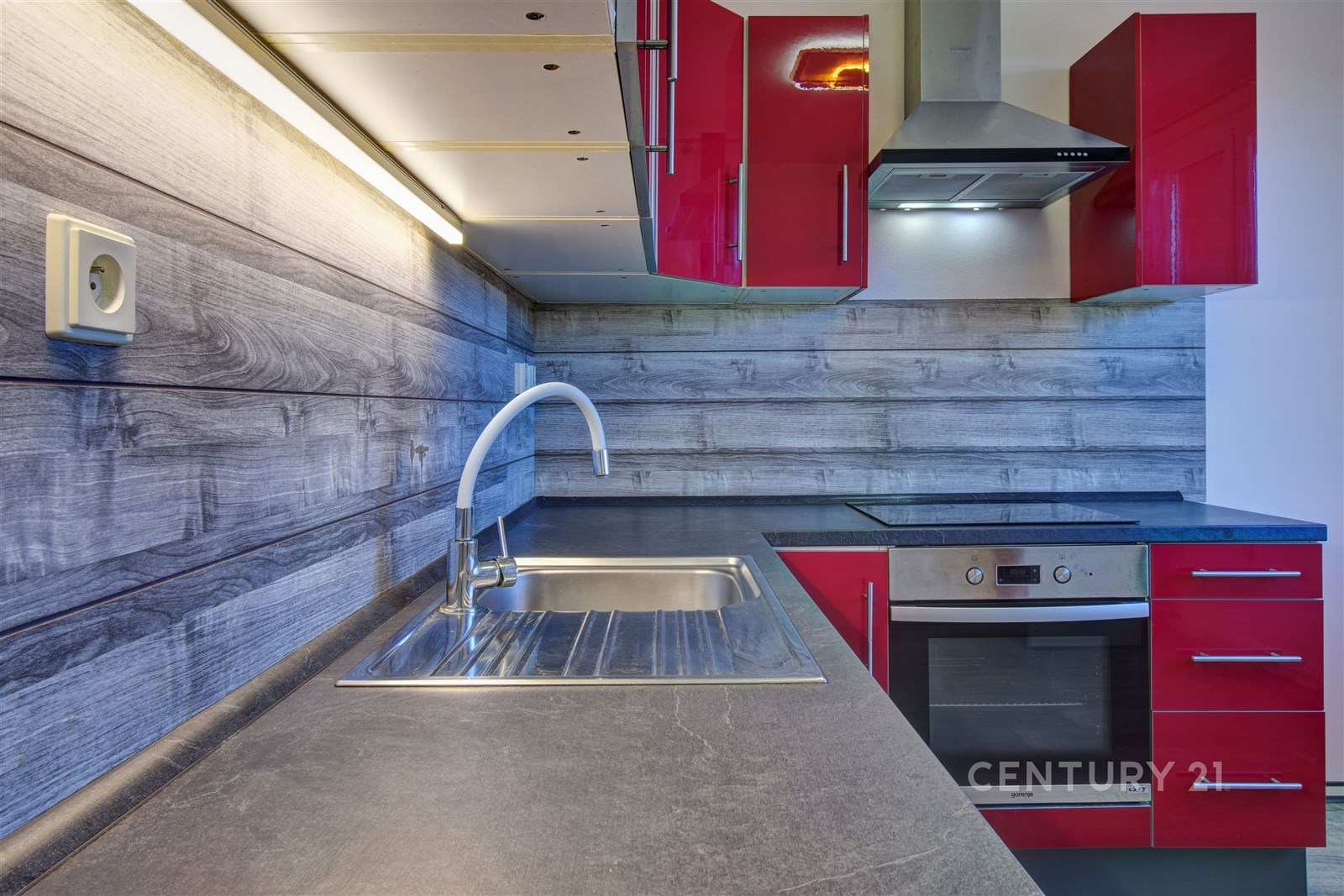 Moderní kuchyň s červenými skříňkami, dřevěným obk