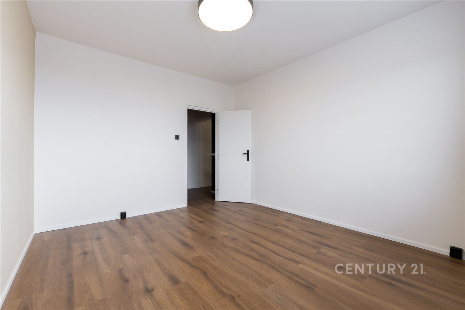 Prázdná ložnice s dřevěnou podlahou, světlé stěny 