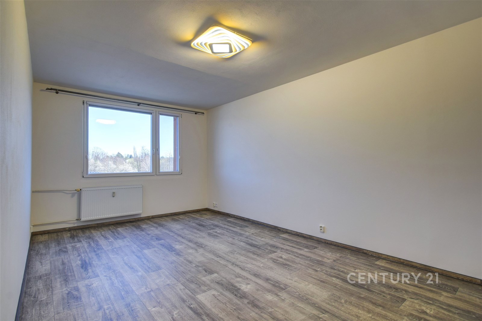 Prázdný světlý pokoj s parketovou podlahou, velkým