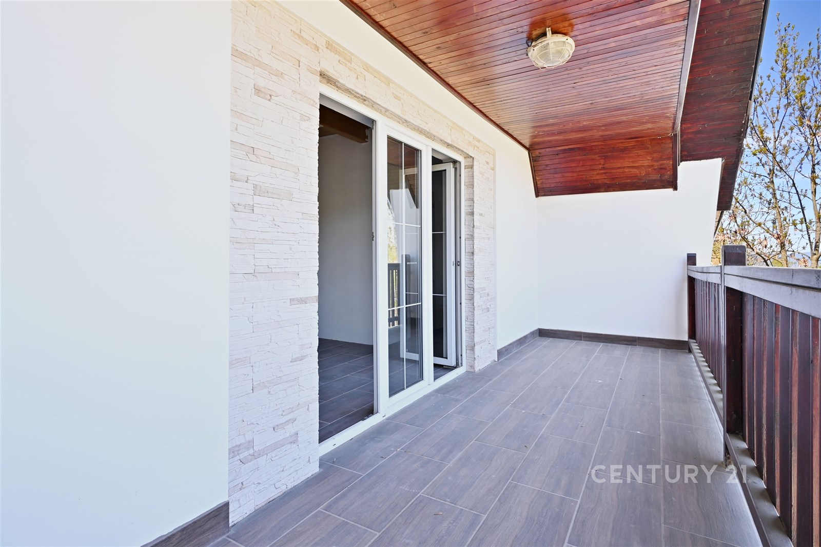 Prostorný balkon s moderní dlažbou, dřevěným podhl