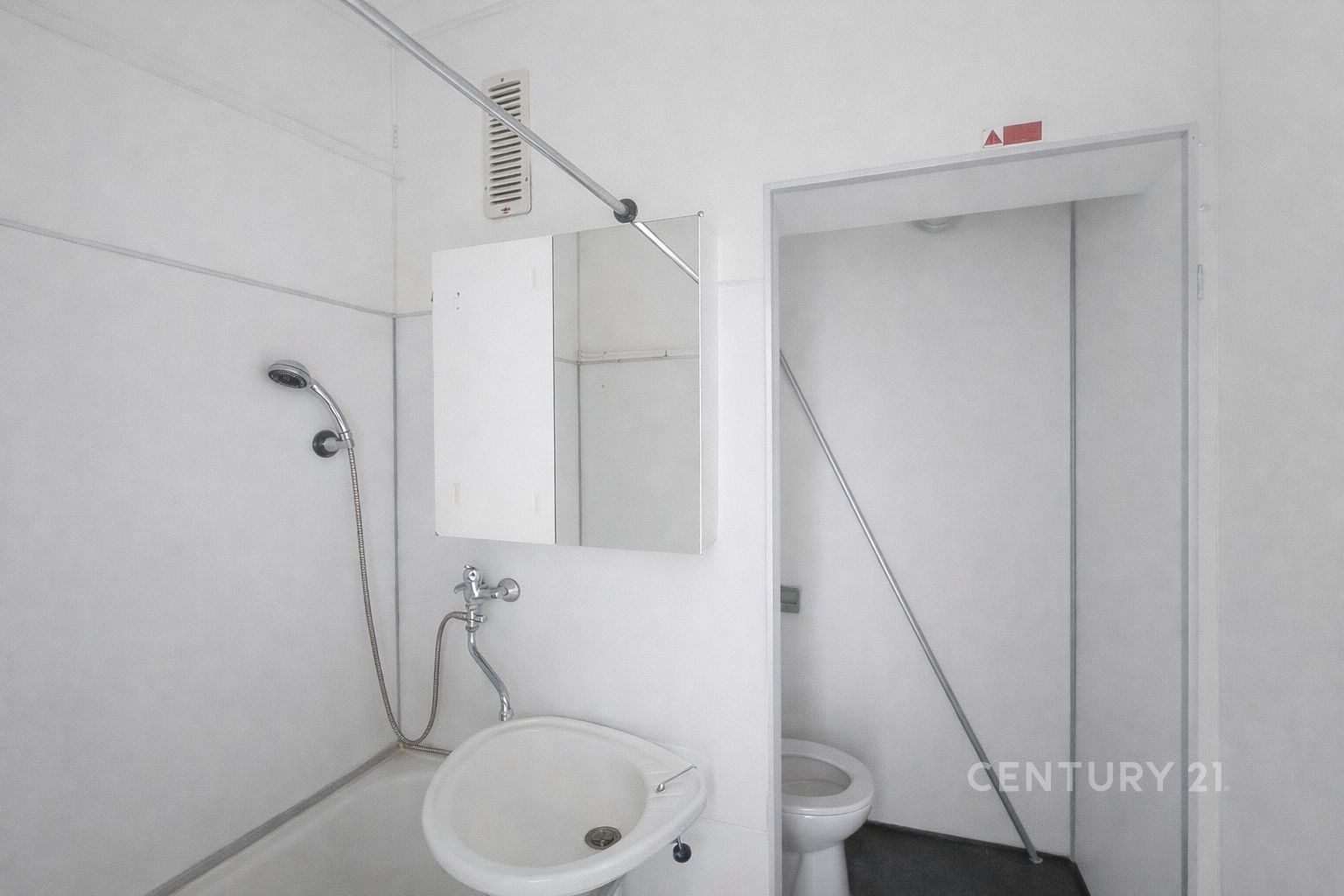 Jednoduchá koupelna s bílými dlaždicemi a umyvadle