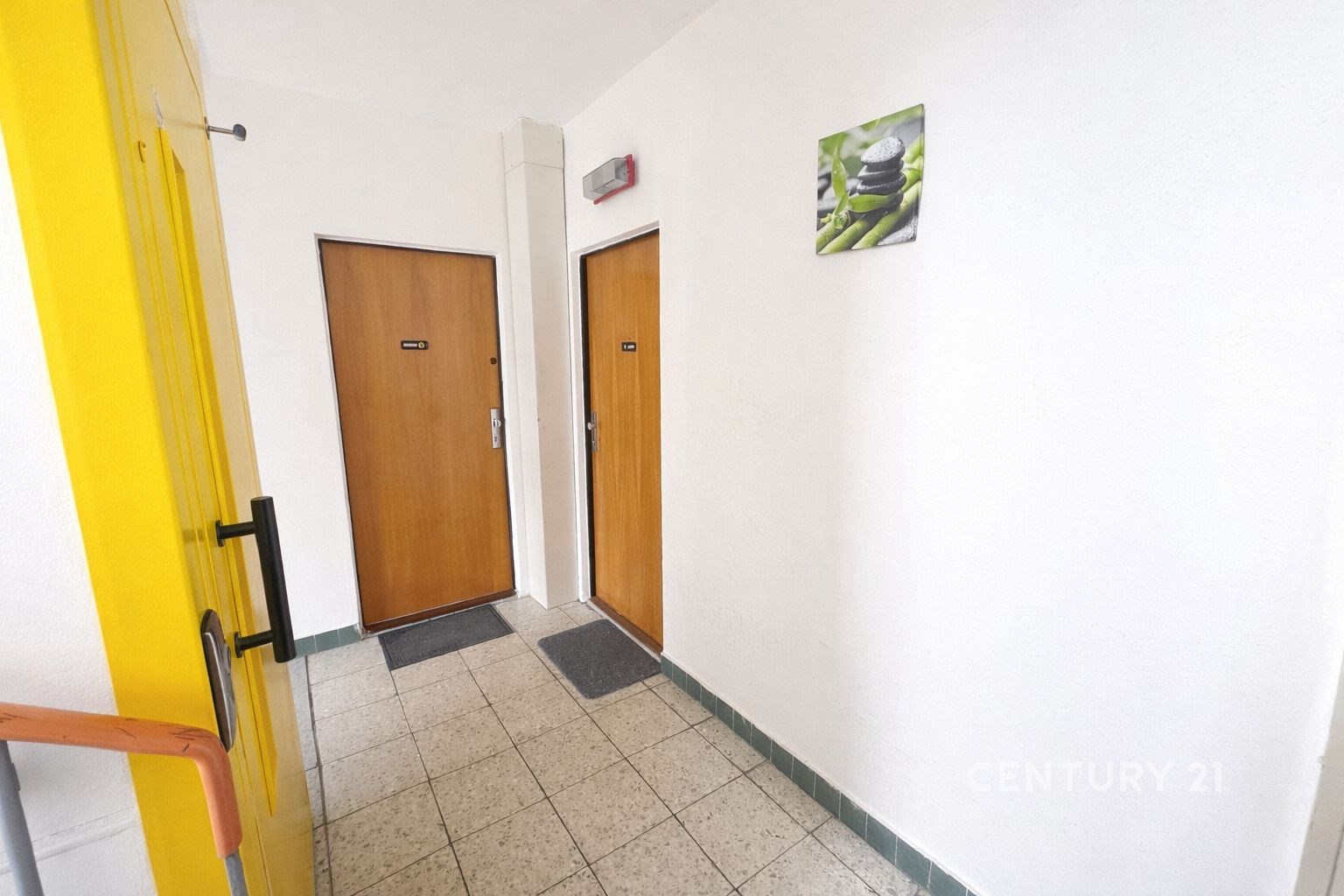 Společná chodba s dlažbou, bílými stěnami a dřevěn