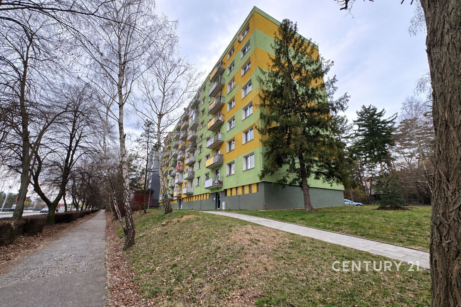 Výškový bytový dům se svěží zeleno-žlutou fasádou,