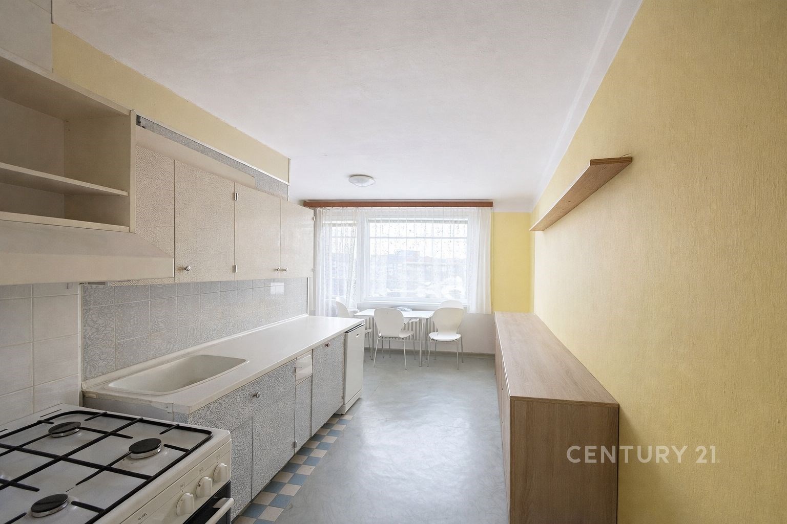 Kuchyně s linoleem a velkým oknem, světlé skříňky,