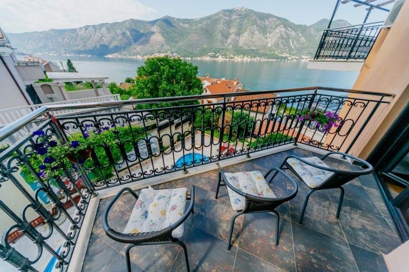 Balkon s dlažbou a kovovým zábradlím nabízí panoramatický výhled na moře. Disponuje pohodlným posezením a květinovou výzdobou.