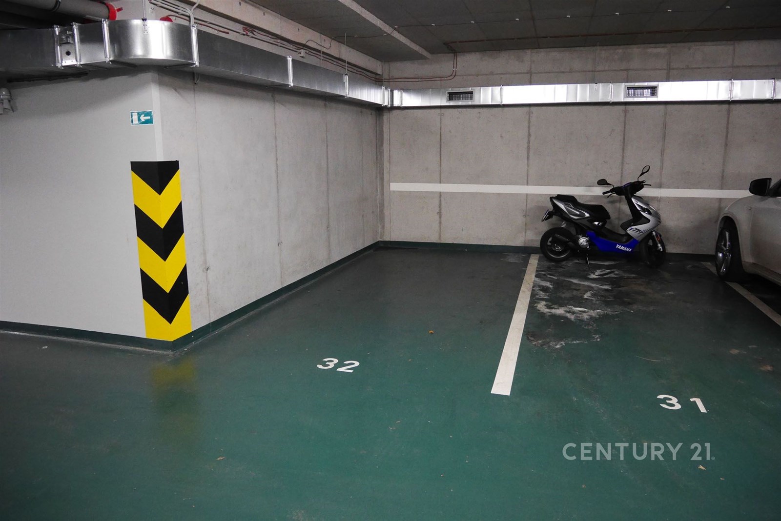 Garážové stání s betonovými stěnami a číslovanými parkovacími místy, vhodné pro auto nebo motocykl, dobře osvětlené a prostorné