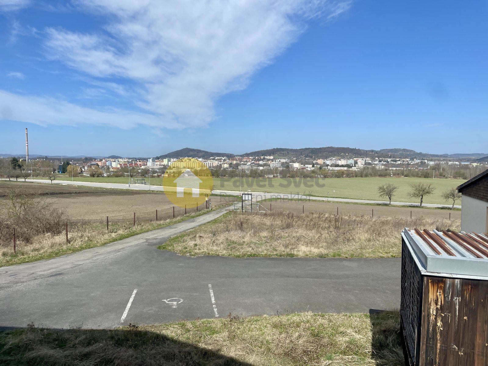 Pohled z areálu na silnici a město. Příjezdová ces