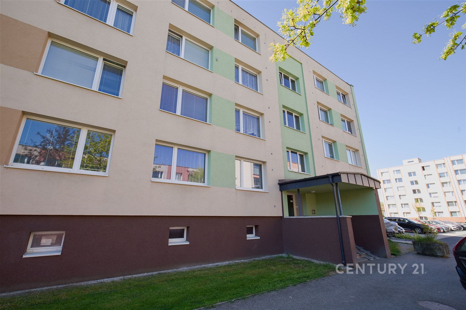 Fasáda bytového domu s moderními okny, čerstvě zateplená, v klidné rezidenční lokalitě, ideální pro rodiny hledající bydlení na předměstí.