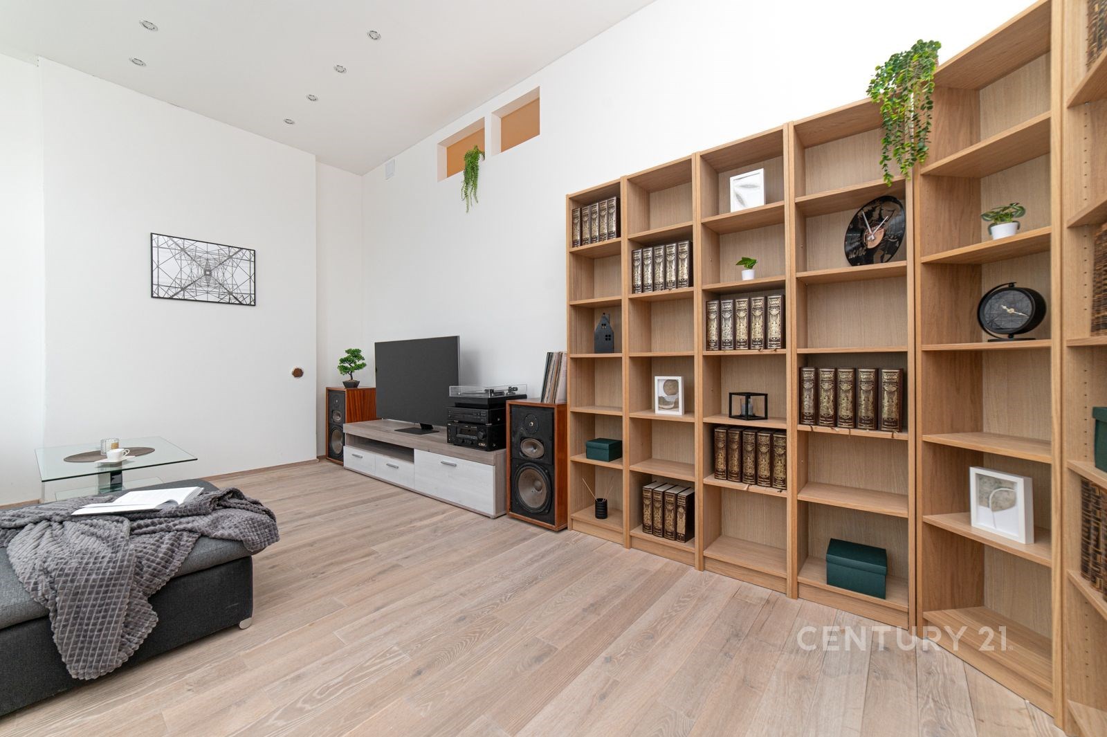 Obývací pokoj s parketovou podlahou, velká knihovna a moderní nábytek, světlý prostor s minimalistickým designem.