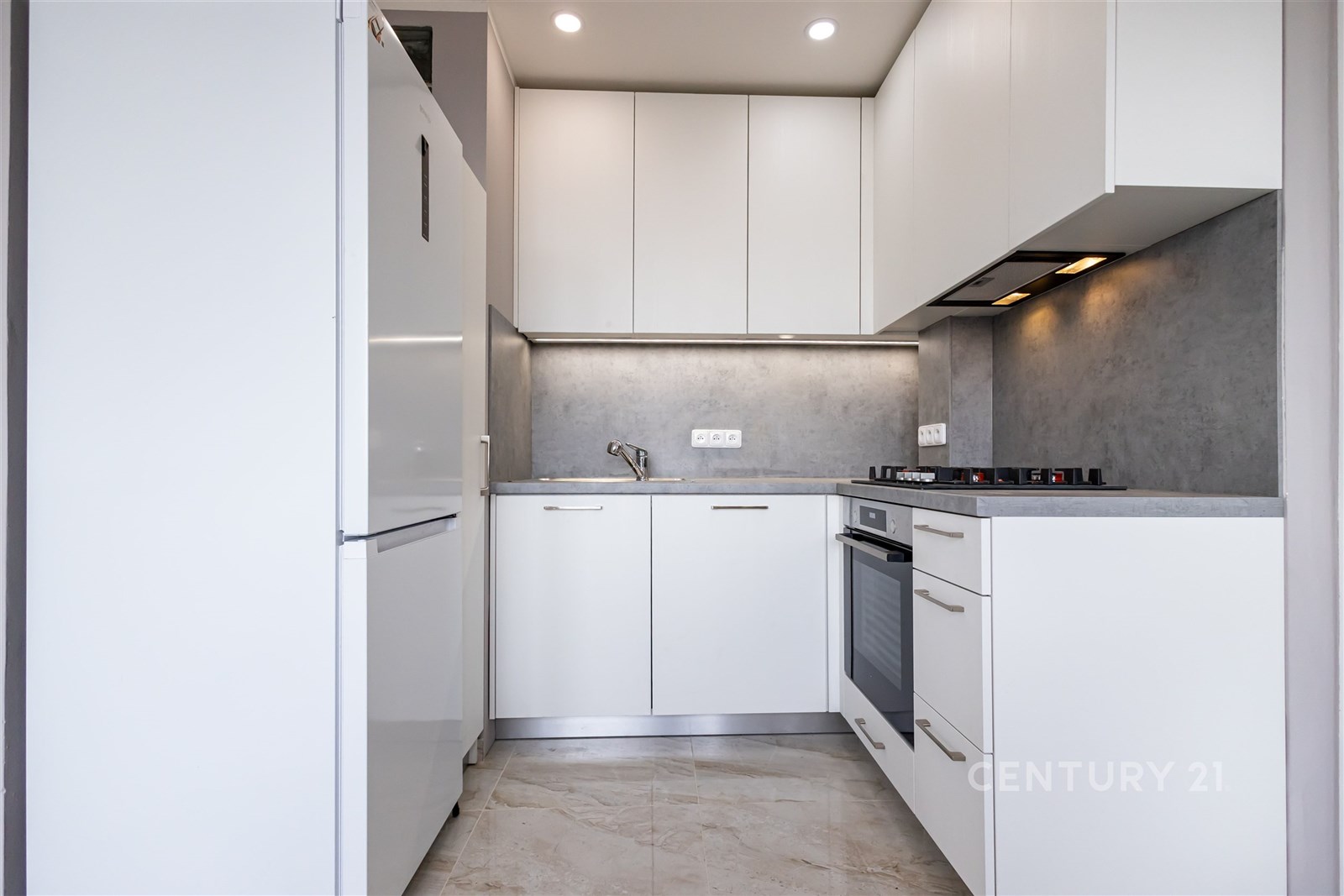 Moderní kuchyň, světlá dlažba a vestavěné spotřebiče, minimalistický design a funkčnost zajišťují komfortní prostředí pro vaření.