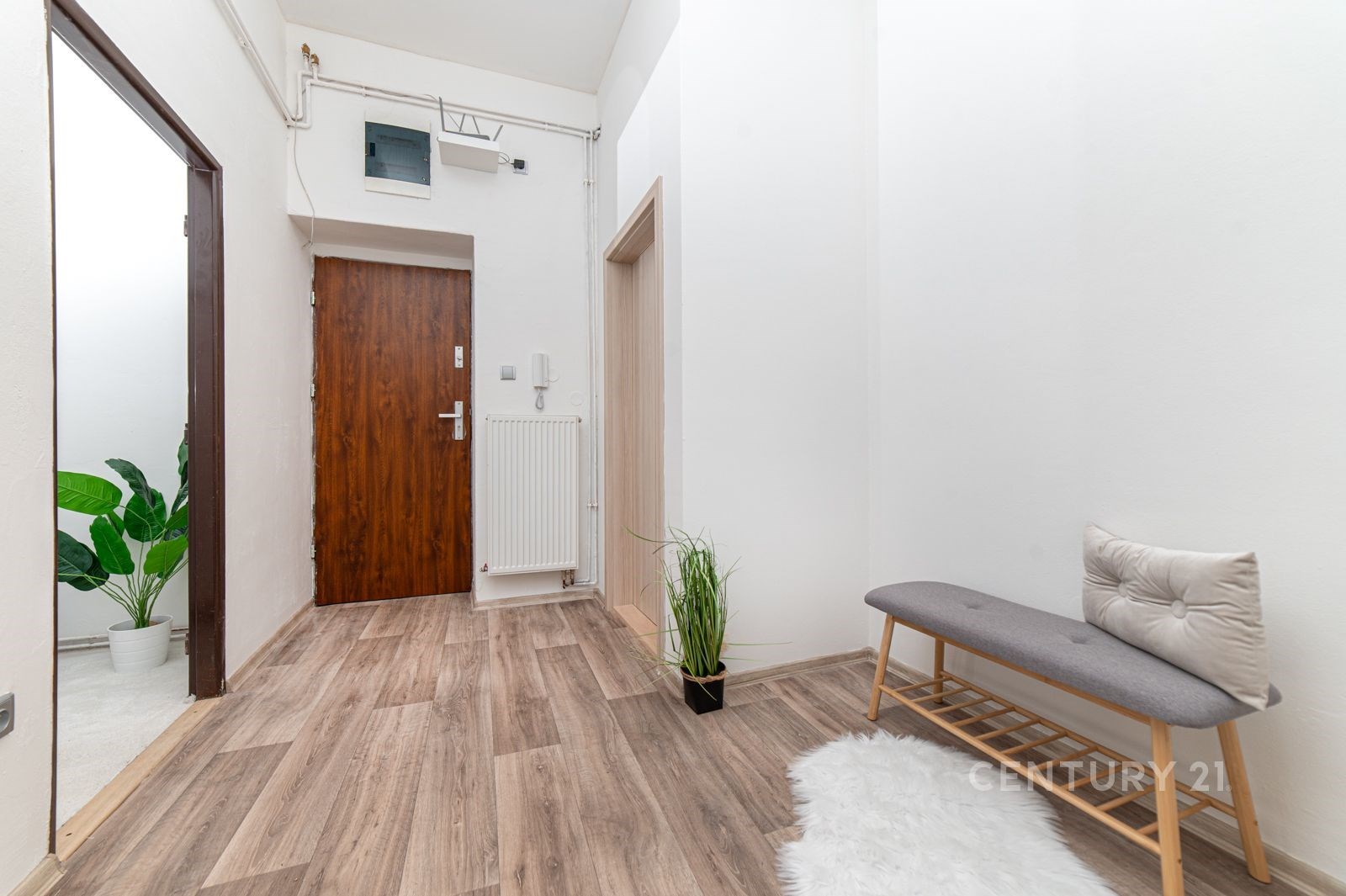 Vstupní hala s moderní vinylovou podlahou, bílými stěnami a dekorativními prvky. Světlý a prostorný interiér s kvalitními materiály.