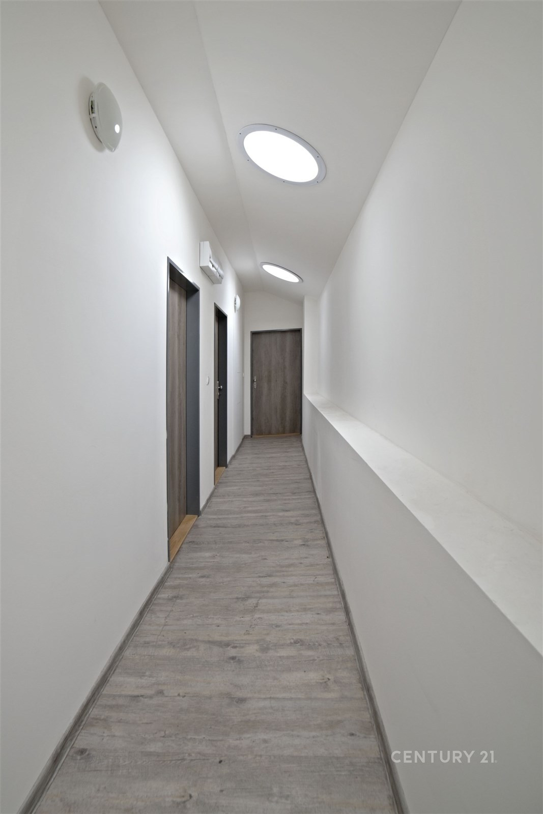 Dlouhá chodba s moderními dřevěnými dveřmi, světlo