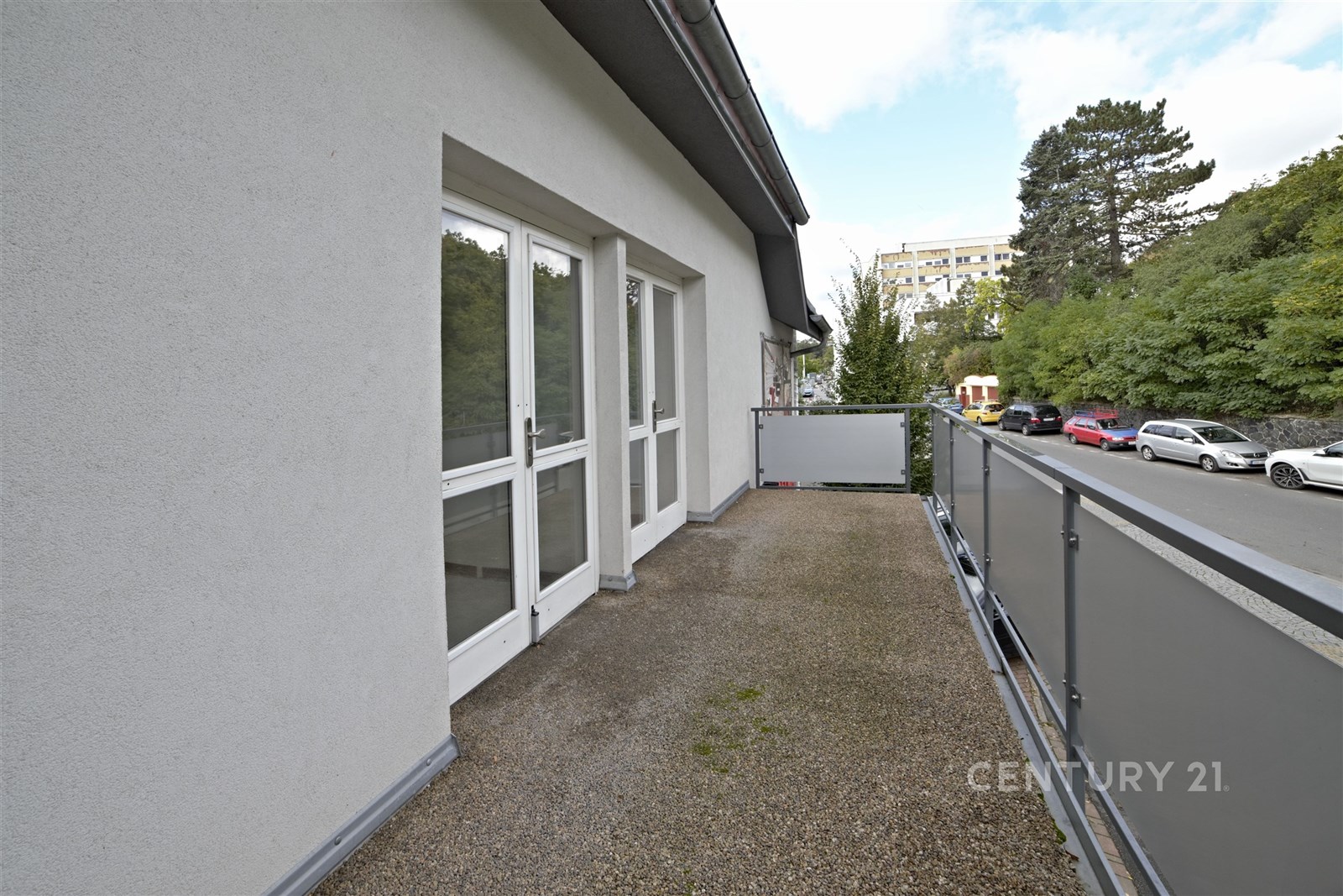 Balkón s kovovým zábradlím, na zemi betonový povrc