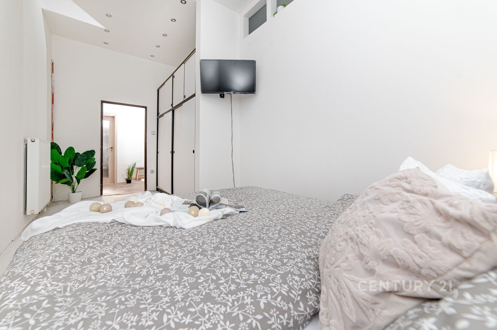Světlá ložnice s moderním designem, vestavěné skříně, parketová podlaha a prostorný interiér s minimalistickými dekoracemi.