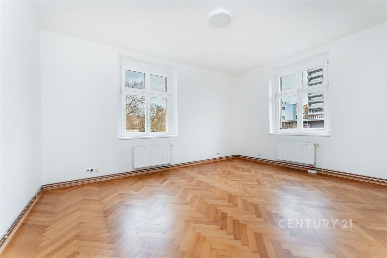 Světlý obývací pokoj s parketovou podlahou, velkým