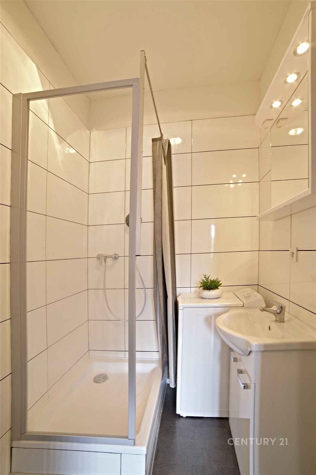 Koupelna s moderní sprchou, bílými obklady a umyva