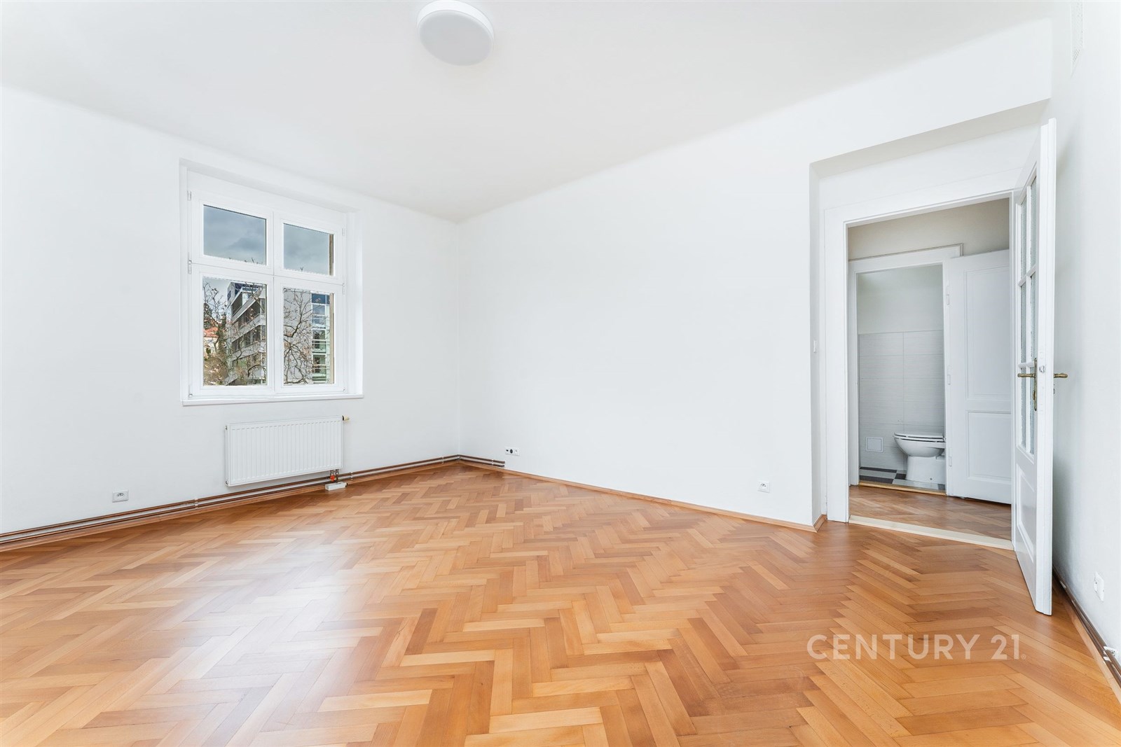 Světlý obývací pokoj s parketovou podlahou, velkým