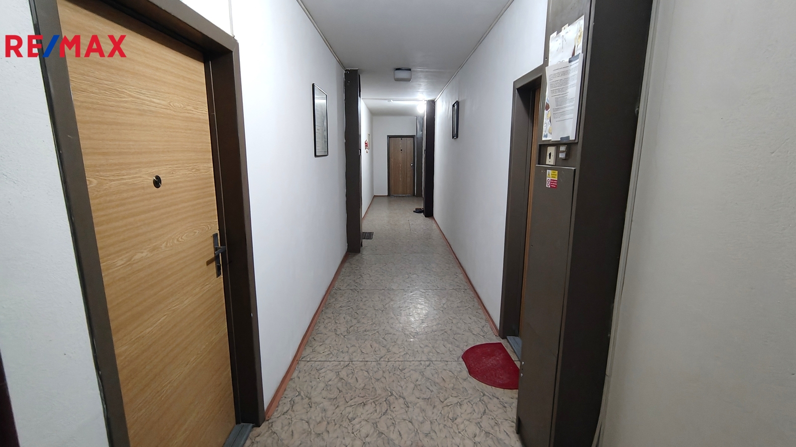 Vlevo dveře k výtahu ve společné chodbě.