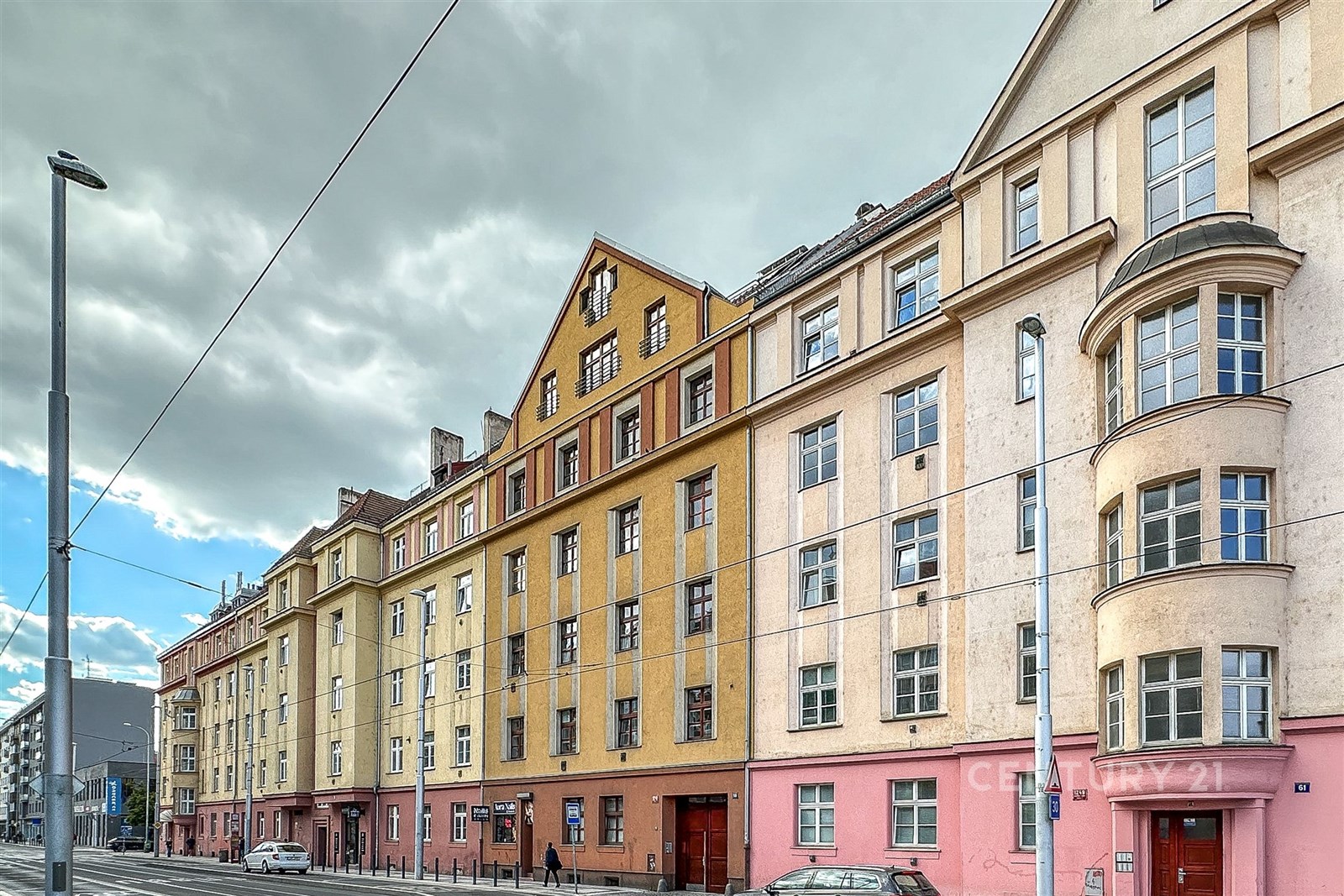 Barevný činžovní dům s historickými detaily, rekonstruovaný, se světlou fasádou a vysokými okny, vhodný pro městské bydlení