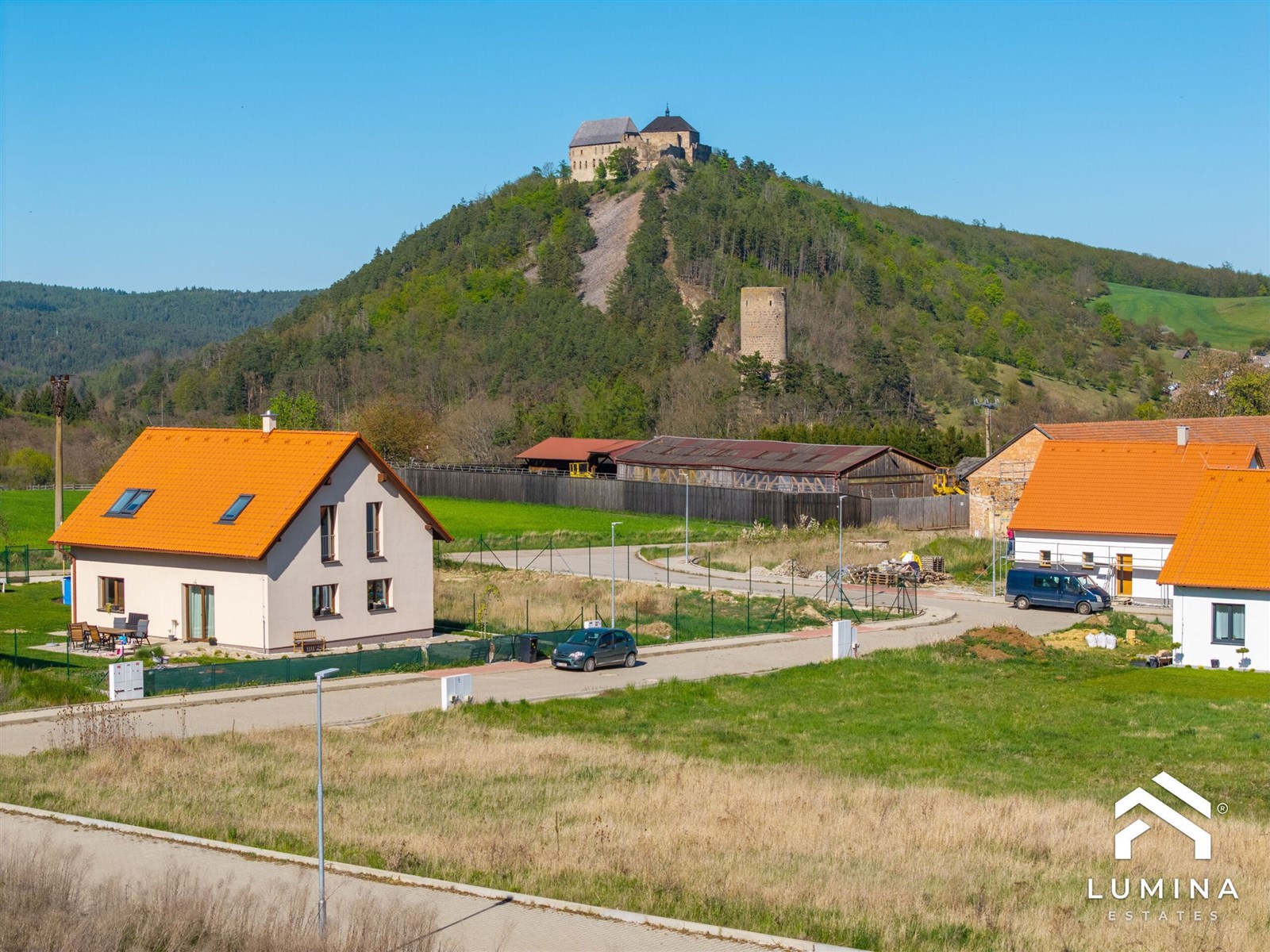 Novostavba rodinného domu s oranžovou střechou, nabízející klidné bydlení. Prostorná zahrada ideální pro rodinu, skvělý výhled na krajinu.