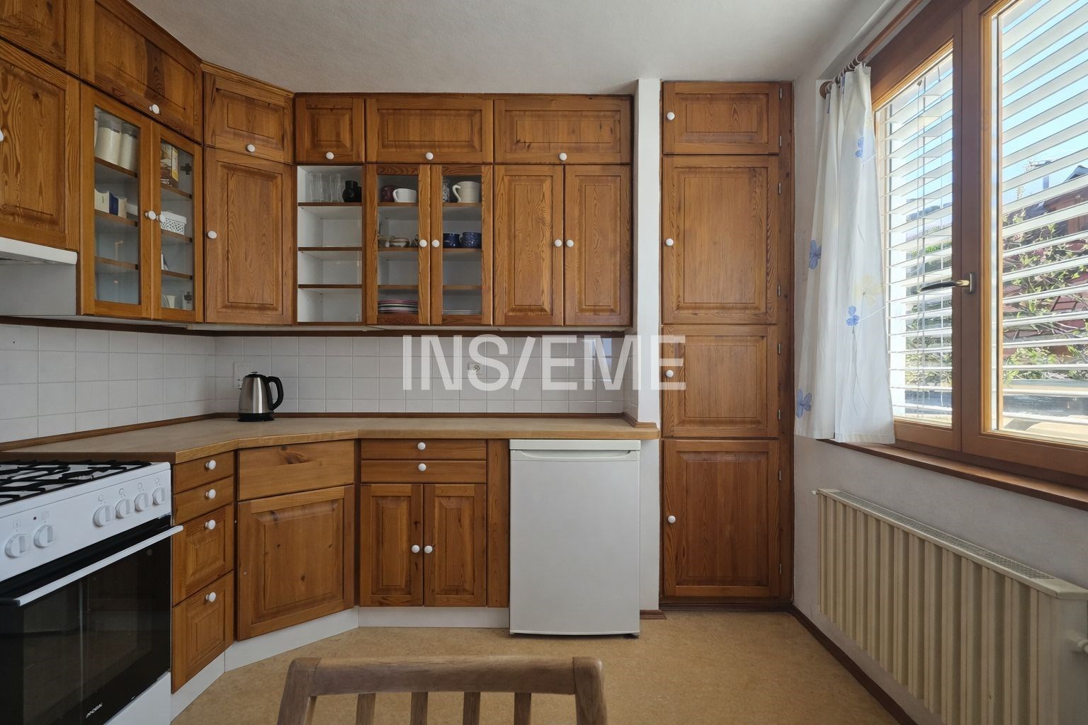 Kuchyň s dřevěnými skříňkami, velkými okny a bílým