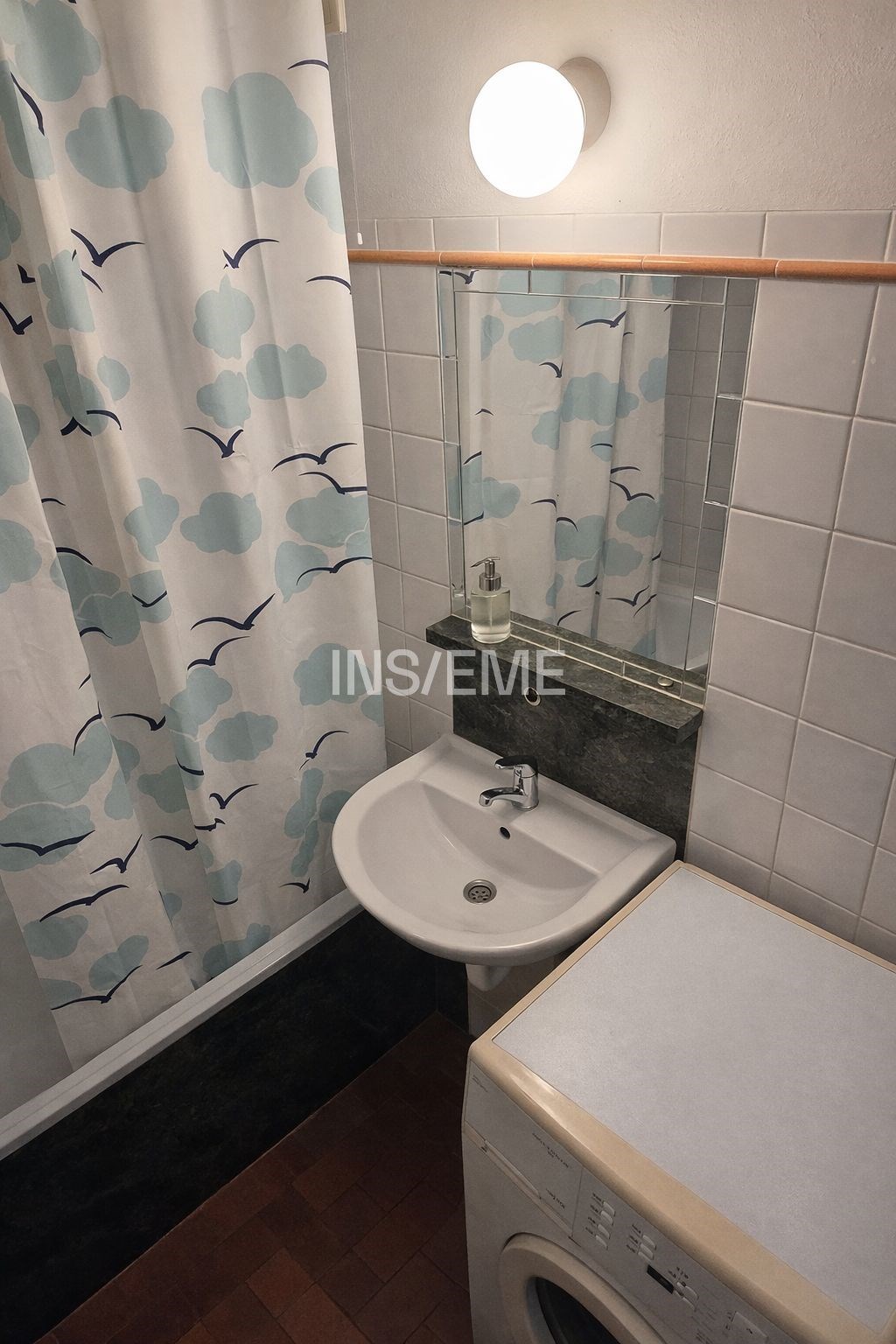 Malá koupelna s dlažbou, umyvadlem a sprchovým kou