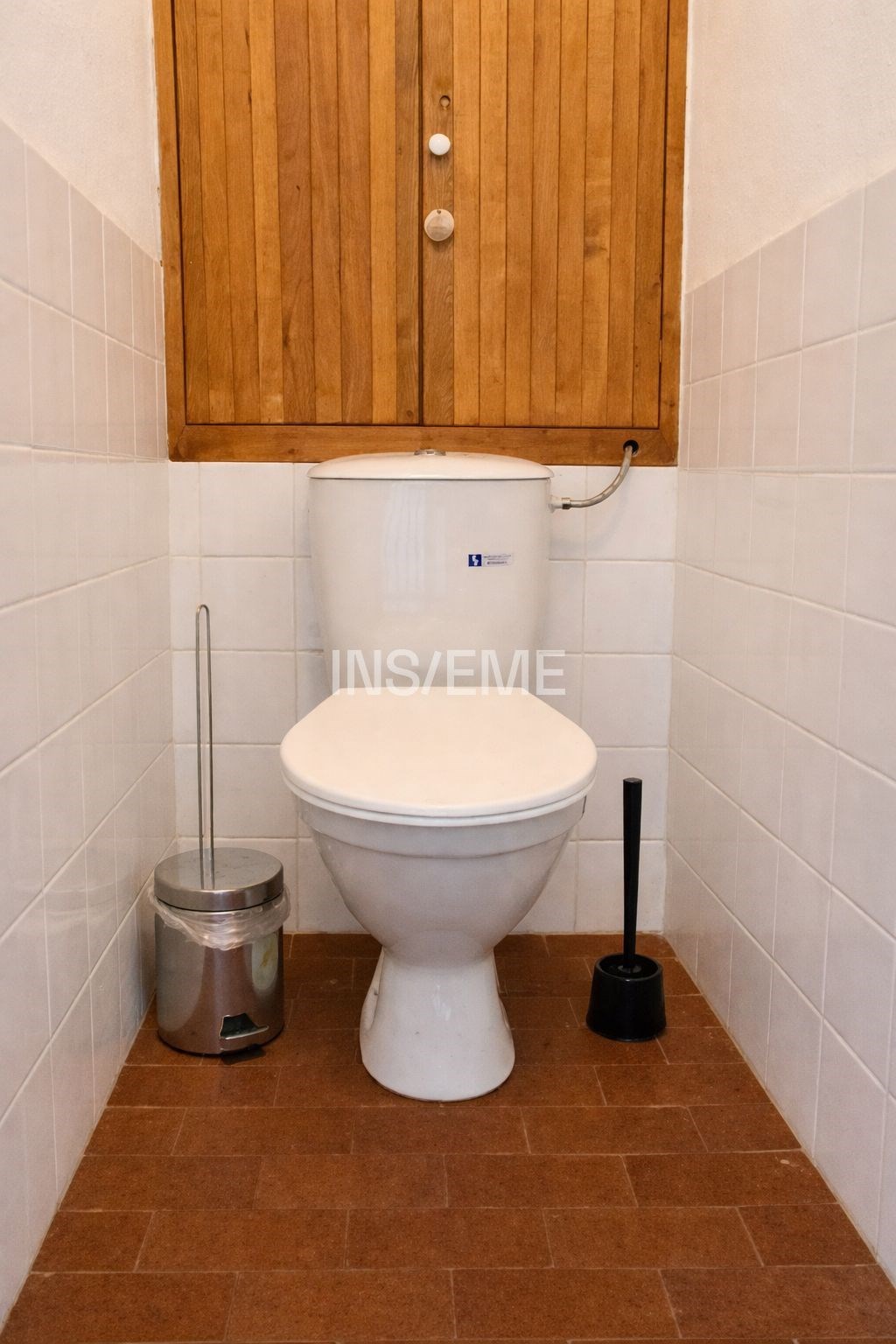 Malá koupelna s dlažbou, dřevěnými dvířky a bílými