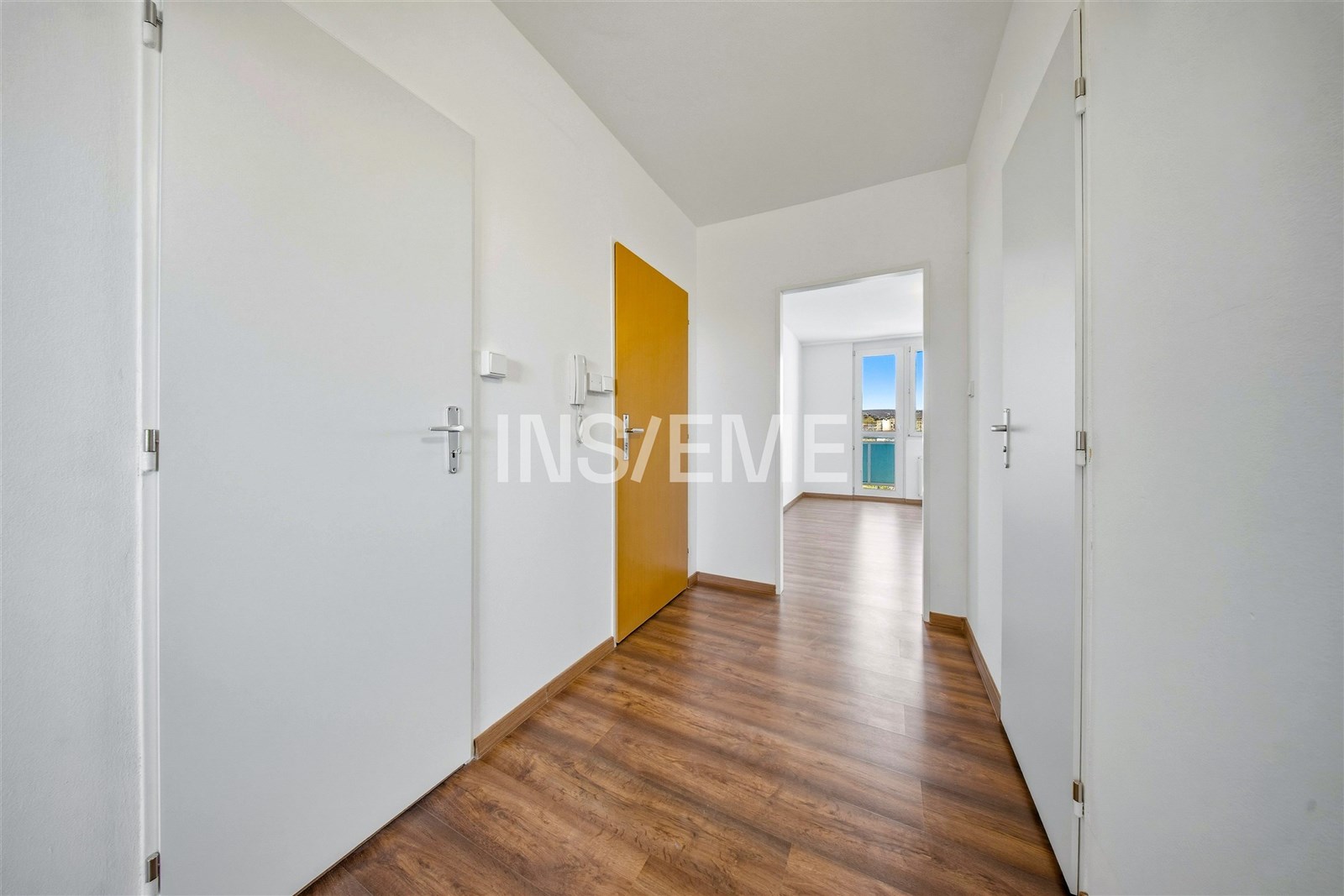 Světlá předsíň s parketovou podlahou a bílými dveřmi nabízí moderní vzhled. Propojení s obývacím pokojem vytváří otevřený a vzdušný prostor.