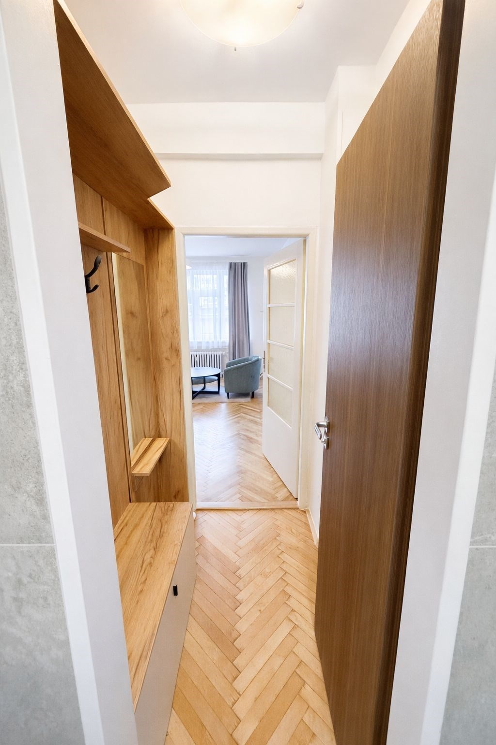 Úzká chodba s dřevěnou vestavěnou skříní a parketo