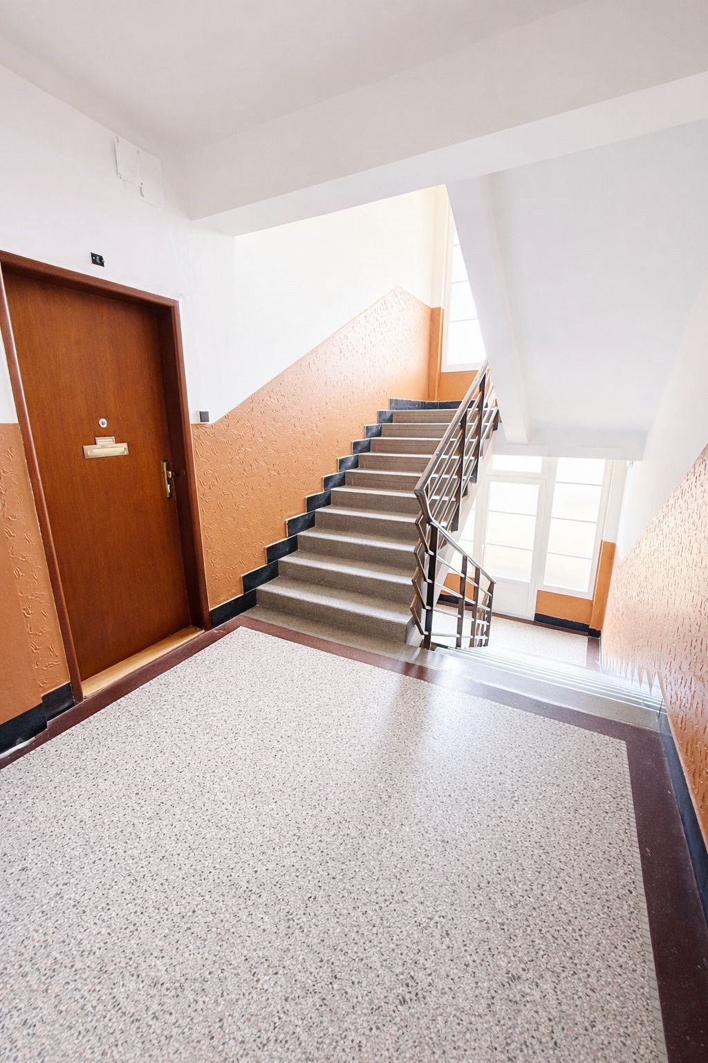 Společné schodiště s teracovou podlahou, velká okn